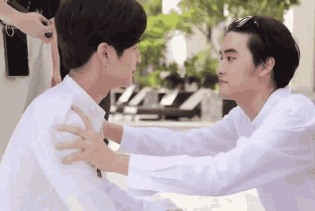 a man in a white shirt is holding another man 's arm