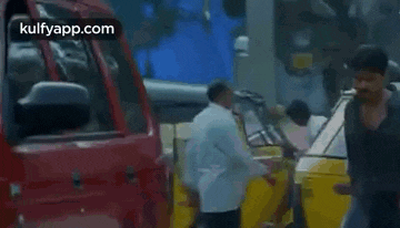 a group of people are walking down a street in front of a red truck and a yellow car .