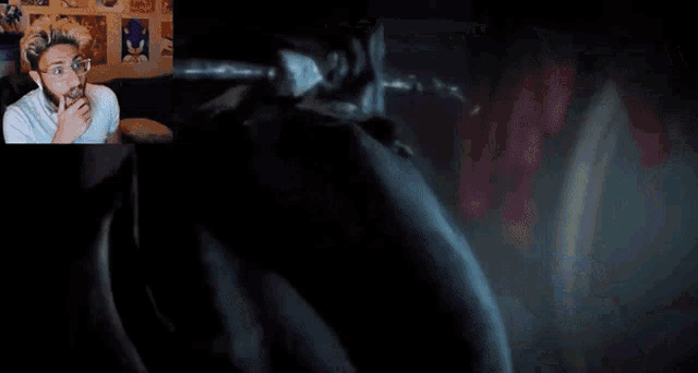 a man is watching a video with a skeleton holding a sword