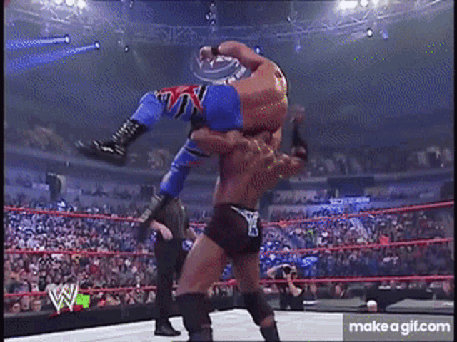 a wrestler is being lifted in the air by another wrestler in a wrestling match .