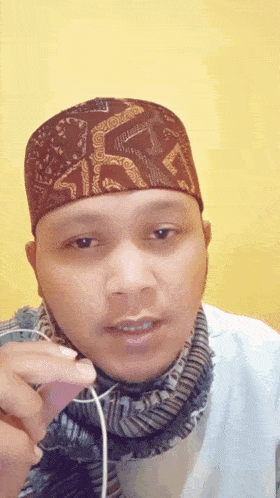 a man wearing a hat and a scarf holds a cord in his hand