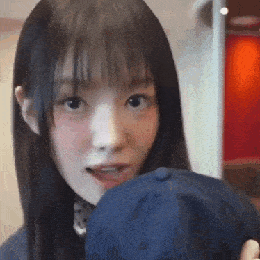 a girl with long dark hair is holding a blue hat
