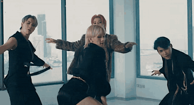 a group of young men and women are dancing in front of a window