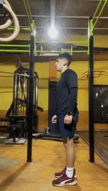 a young man in a black shirt and red shoes is standing in a gym