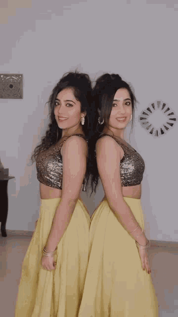 two women wearing crop tops and yellow skirts are posing for a photo