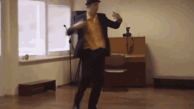 a man in a suit and hat is dancing in a room with a piano