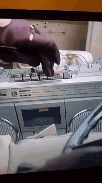 a close up of a cassette player with a person 's hand on it