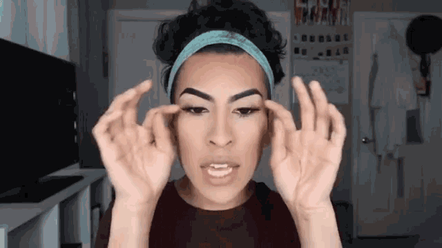 a woman wearing a headband is making a face with her hands