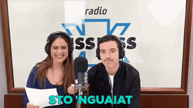 a man and a woman wearing headphones are standing in front of a microphone .