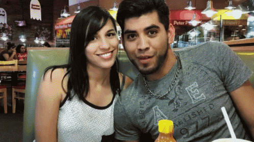 a man and a woman are posing for a picture in a restaurant and the man is wearing an american eagle shirt