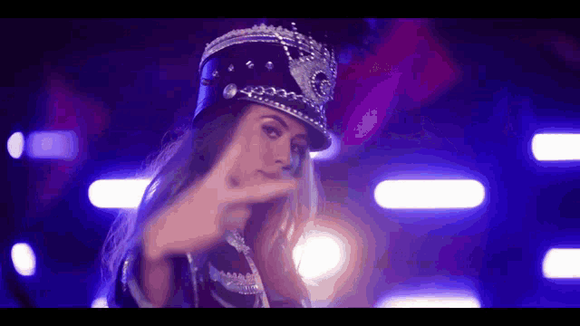 a woman wearing a hat with a crown on it makes a peace sign