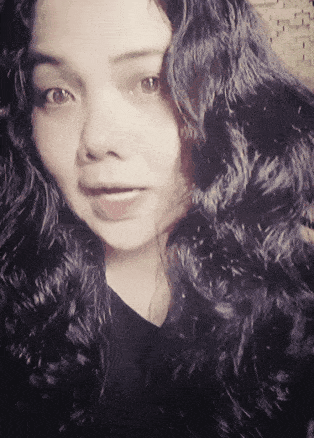 a woman with long curly hair is looking at the camera