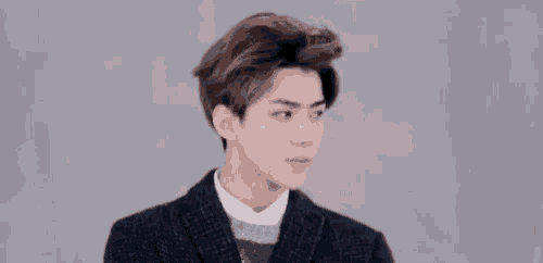 a close up of a young man wearing a suit and a sweater .
