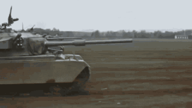 a tank is driving through a field with smoke coming out of its cannon