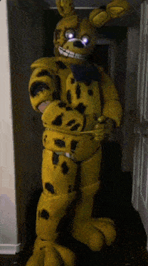 a person in a yellow bunny costume is standing in a hallway with their arms crossed .