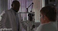 a man in a lab coat talking to another man in a hospital room .