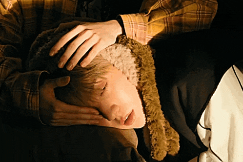a person in a plaid shirt is laying down with their hand on their head