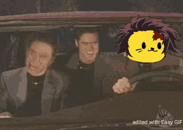 a gif of two men in a car with a yellow cat with a red spot on his head