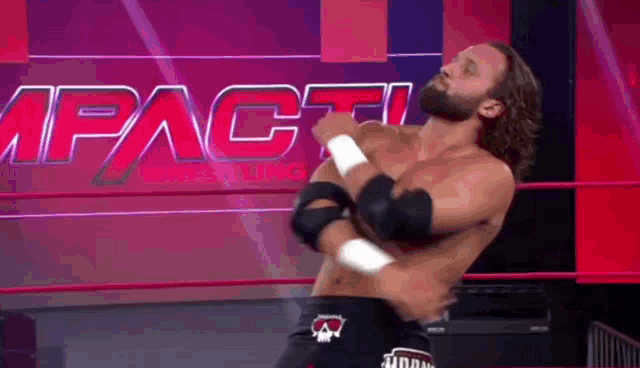 a man with a beard is standing in a wrestling ring with his arms outstretched .