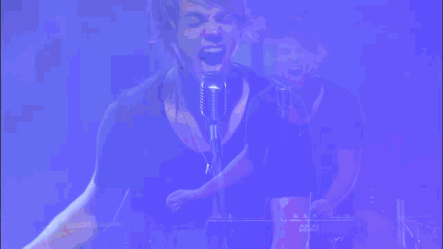 a man is singing into a microphone with a blue background