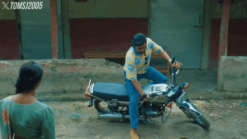a man standing next to a motorcycle with xtomsj2005 written on the bottom right