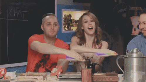 a man and a woman are sitting at a table with their arms outstretched in front of a sign that says chat