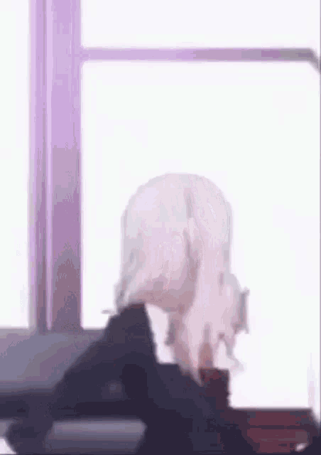 a girl is sitting in front of a window and looking out the window .