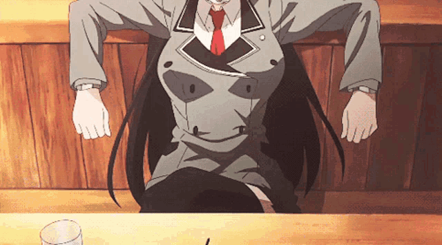 a woman in a suit and tie is sitting at a table