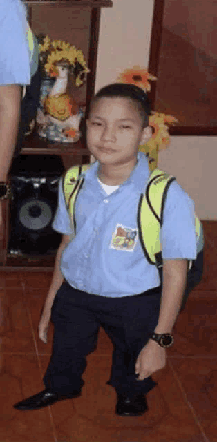 a young boy wearing a blue shirt and black pants with a yellow backpack on his back