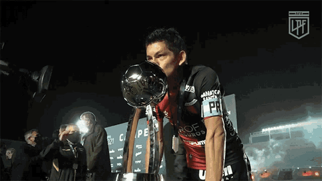 a man holding a trophy with the letter lp on his shirt