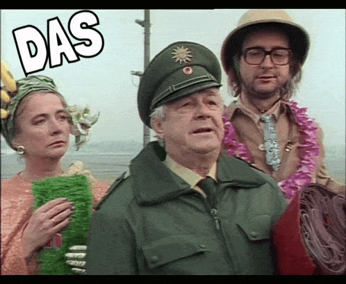 a man in a military uniform stands next to a woman and a man in a safari hat with the word das above them