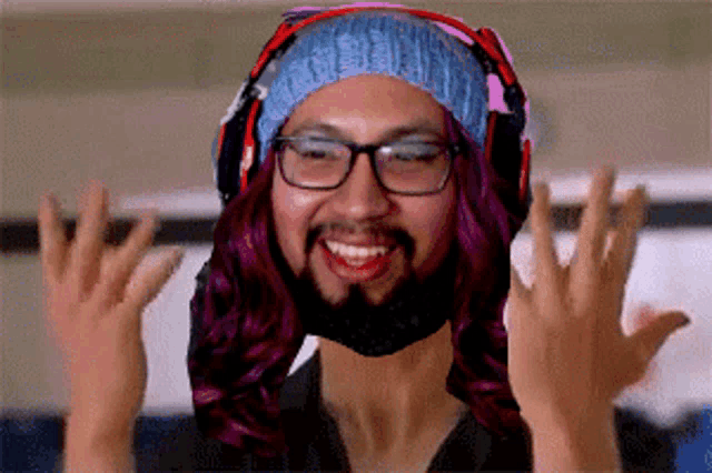 a man with purple hair and a beard is wearing headphones and a beanie