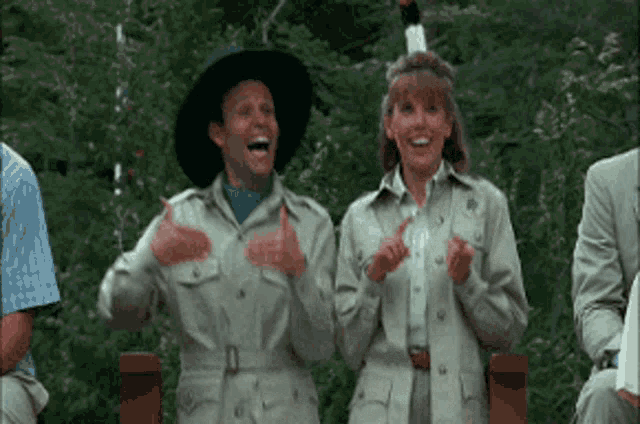 a man and a woman in safari outfits are clapping and laughing