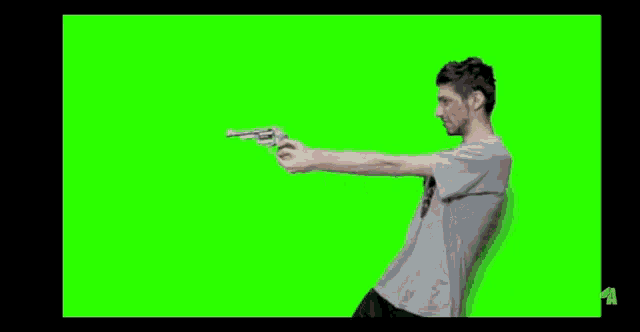 a man is holding a gun in his hand on a green screen .