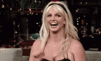 a blonde woman is sitting on a couch laughing .