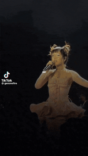 a woman in a white dress is singing into a microphone on stage