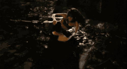 a woman is swimming in a body of water with a gun .