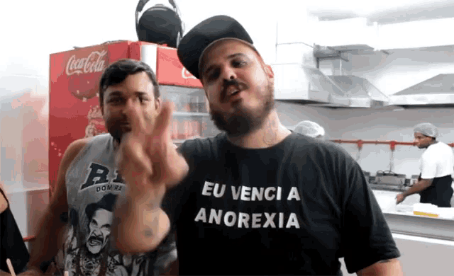 a man wearing a shirt that says eu venci a anorexia giving a peace sign