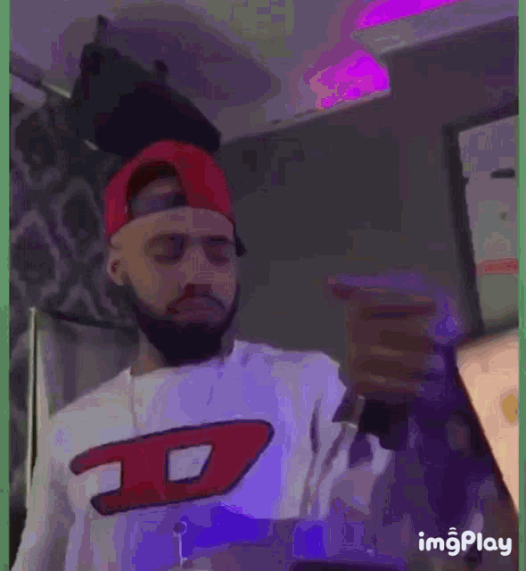 a man with a beard wearing a red hat and a white shirt with the letter d on it