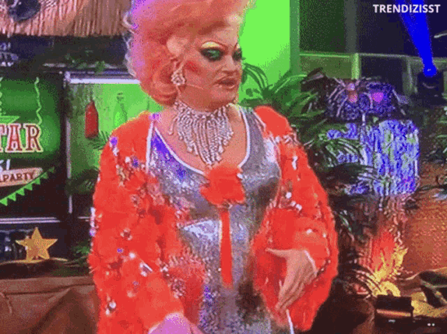 a drag queen is standing in front of a sign that says star party