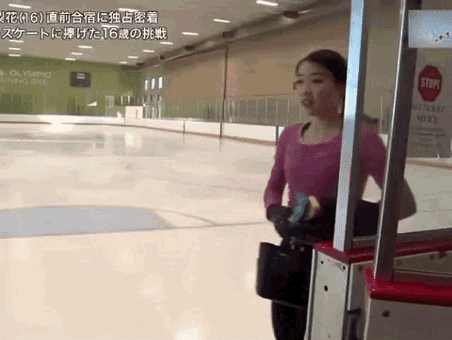 a woman stands in front of an ice rink that has a stop sign on it