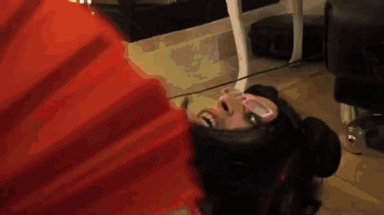 a woman is laying on the floor with a red fan .
