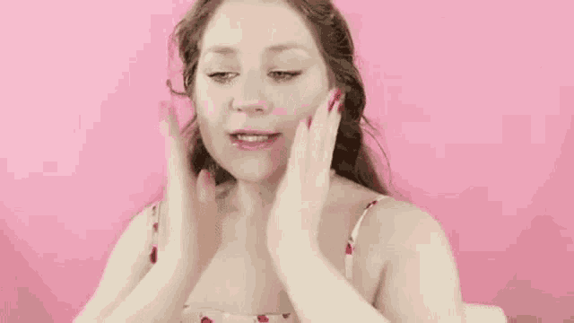 a woman with red nails is covering her face with her hands and smiling .