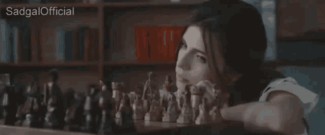 a woman is playing a game of chess and the words sadgal official are on the bottom