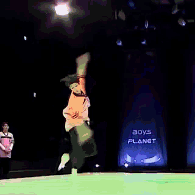 a man is jumping in the air in front of a boys planet sign