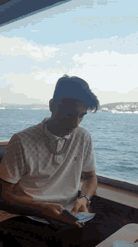 a man wearing a louis vuitton shirt is looking out a window at the water
