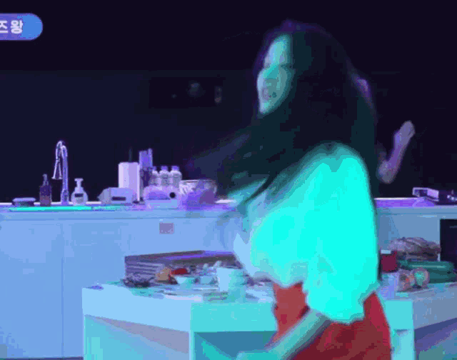 a woman in a red skirt is dancing in a kitchen with a blue sign that says ' a ' on it