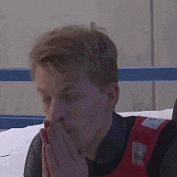 a man is covering his mouth with his hands while wearing a life jacket .