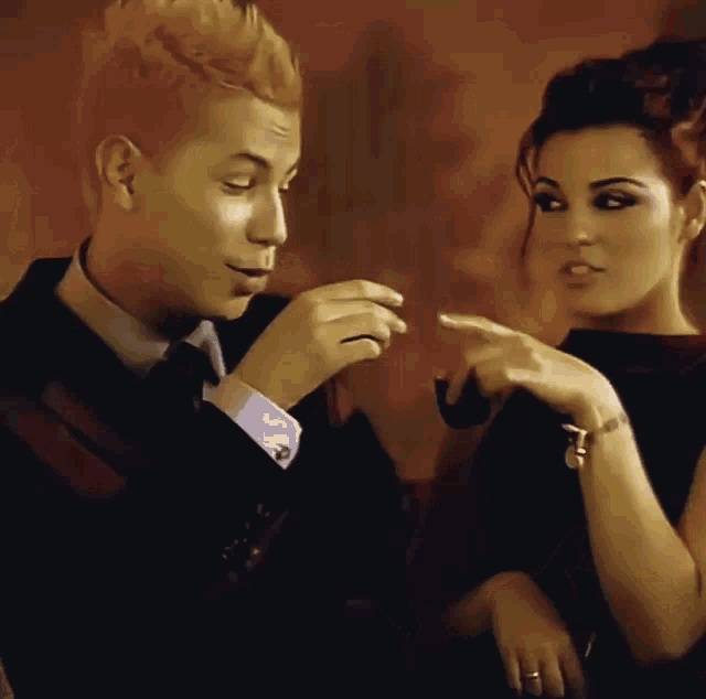 a man in a suit and tie smoking a pipe next to a woman
