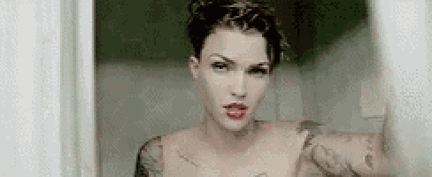 a woman with tattoos on her arms and chest is taking a selfie in front of a mirror .